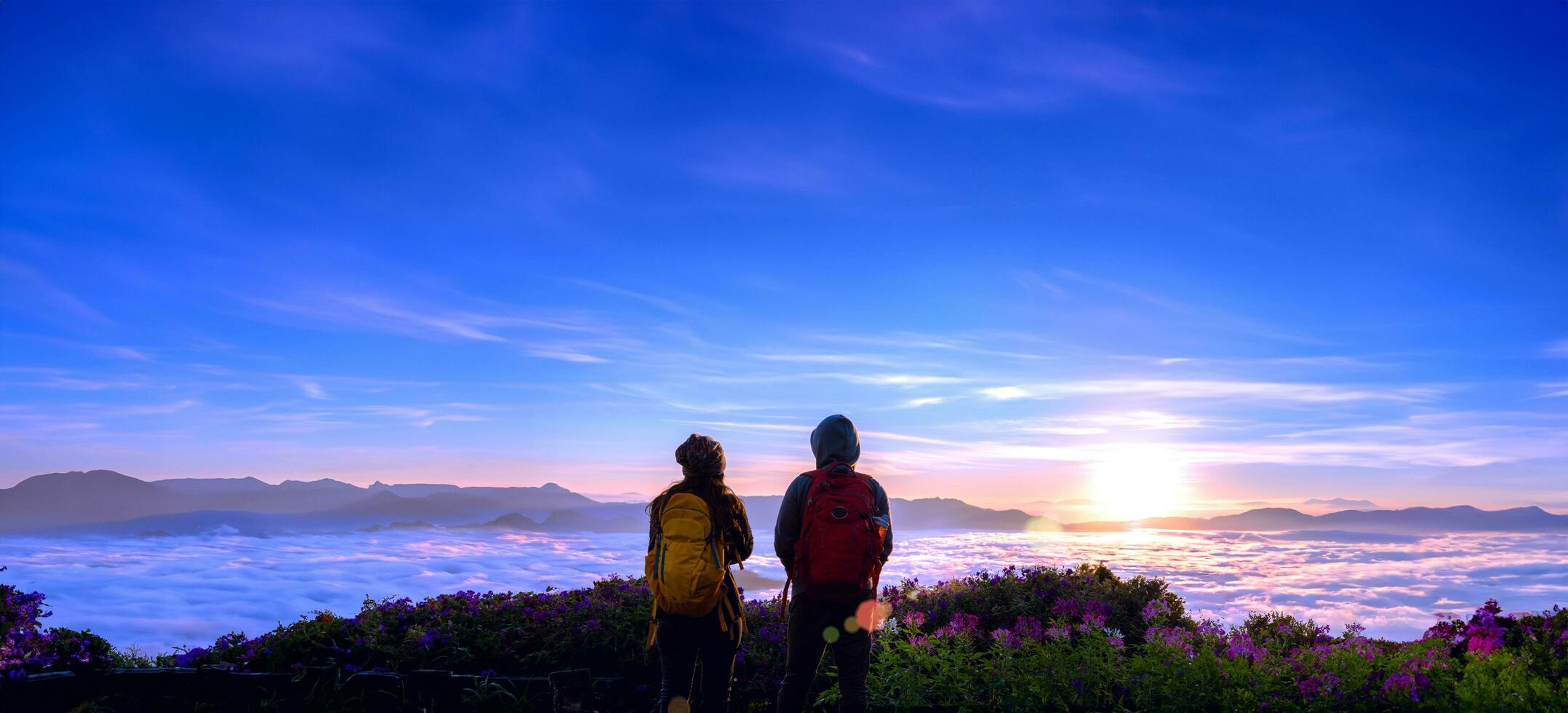 asiatische paartouristen mit rucksäcken, die blick auf die landschaft auf den berg, die schöne landschaft und das licht der schönen sonne am himmel beobachten foto