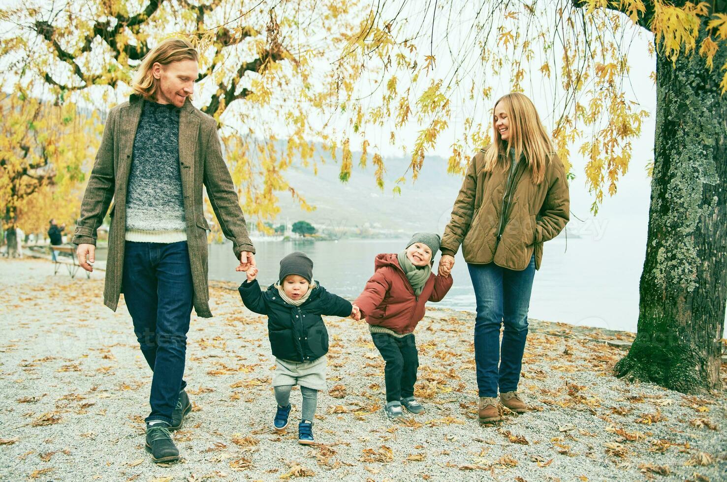 draussen Porträt von jung glücklich Familie von vier, Mutter und Vater spielen mit Kinder im Herbst Park durch das See, kalt Wetter foto