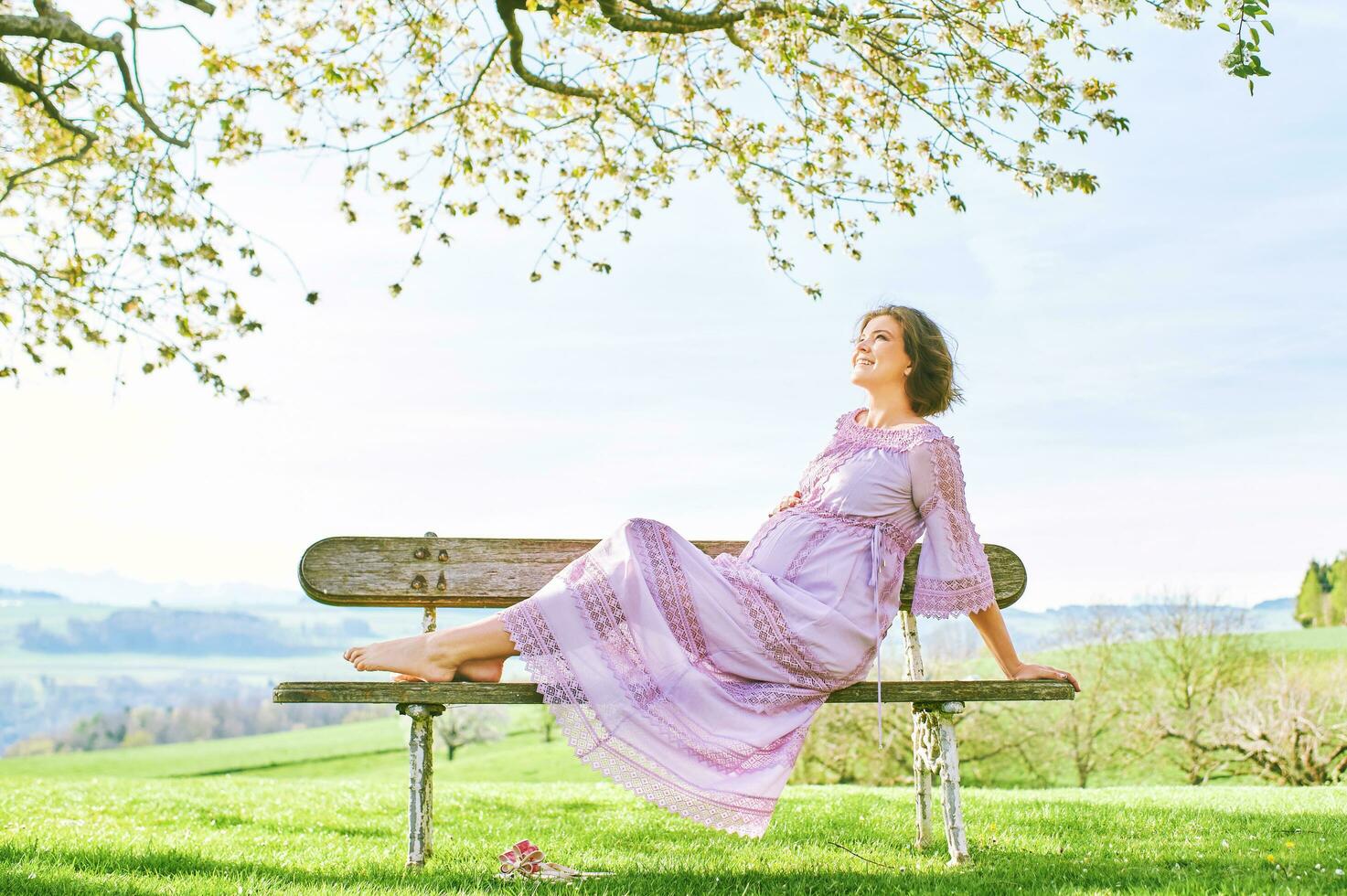 draussen Porträt von glücklich schwanger Frau genießen nett sonnig Tag im Frühling Garten foto