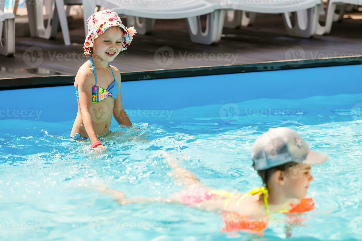 zwei wenig Mädchen spielen im das Schwimmbad foto