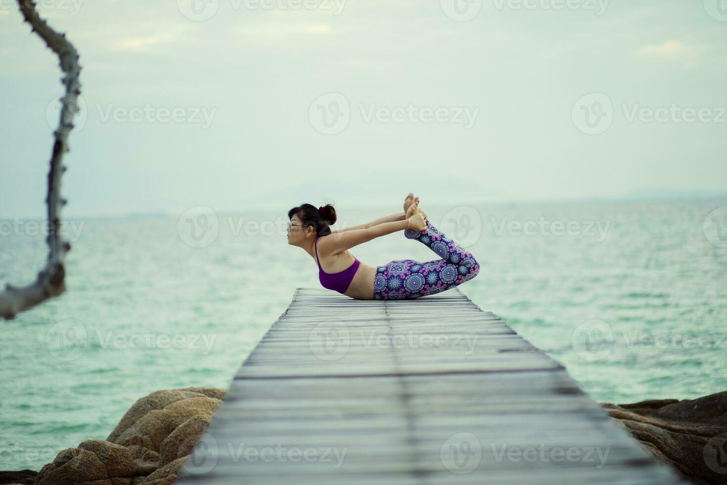 schön Frau spielen Yoga im Schildkröte Pose auf Meer hölzern Seebrücke foto
