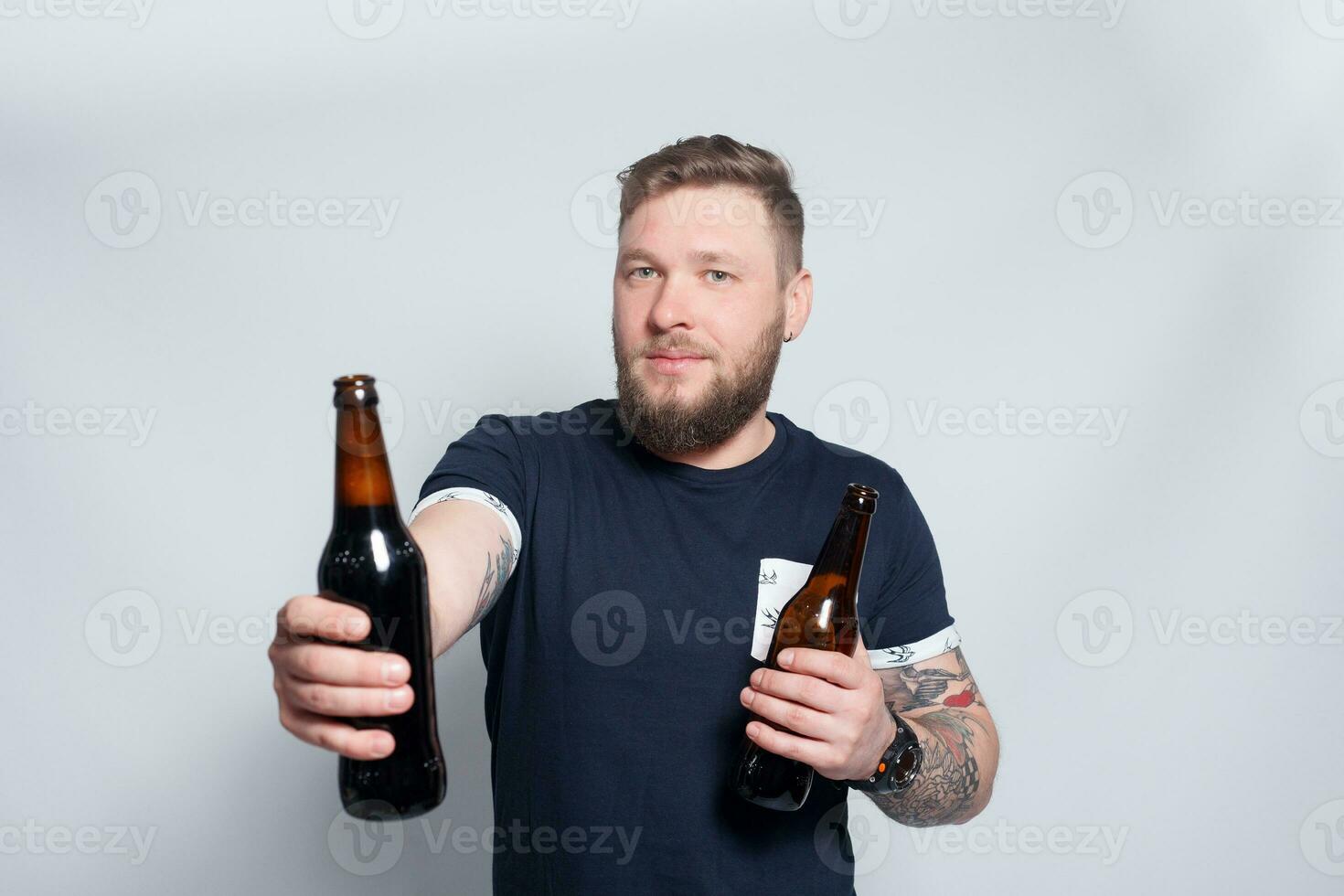 brutal bärtig männlich mit tätowiert Arm Getränke ein Bier von ein Flasche. foto