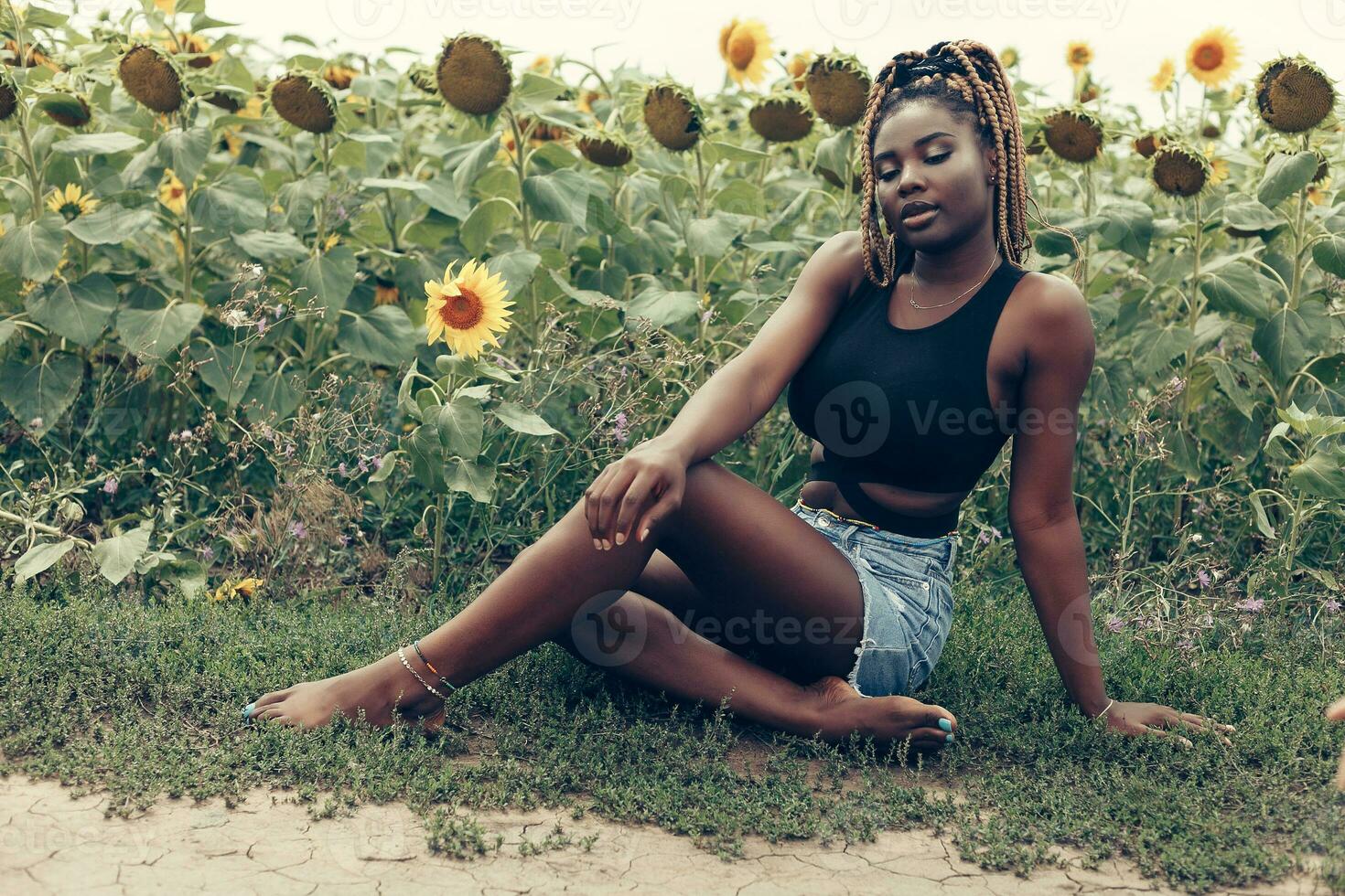 afrikanisch amerikanisch Mädchen im ein Feld von Gelb Blumen beim Sonnenuntergang foto