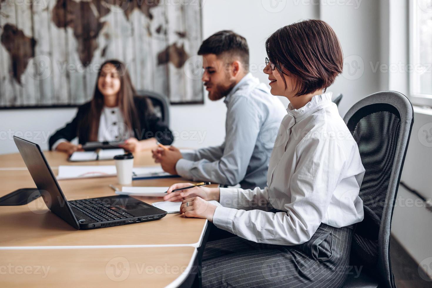 attraktives Mädchen, das am Laptop arbeitet, während es sich mit ihrem Personal trifft foto