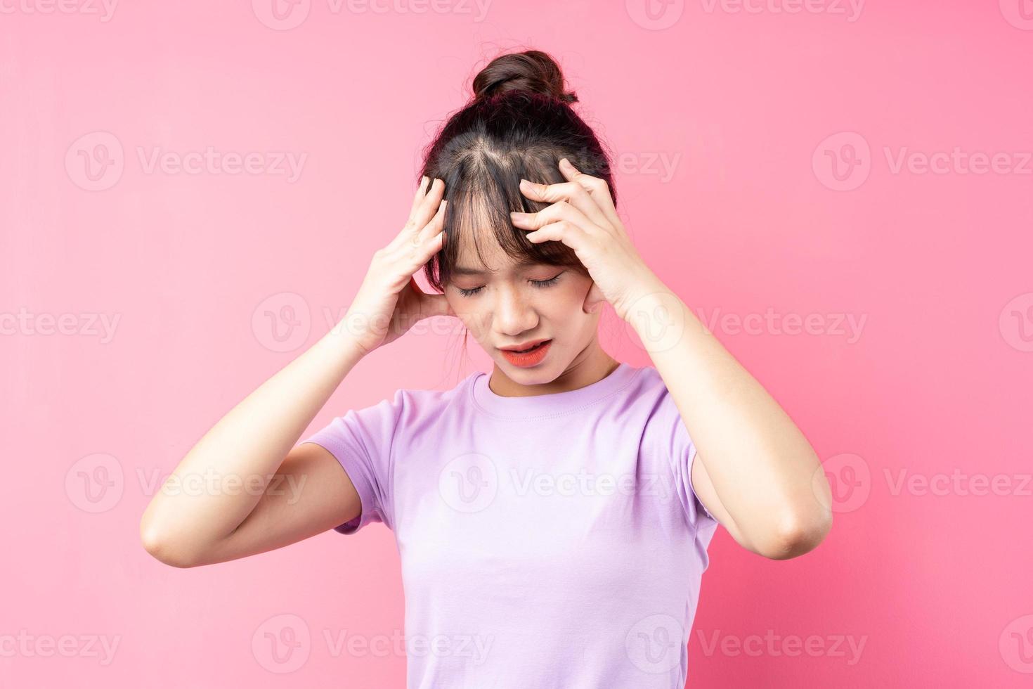 Mädchenporträt mit Kopfschmerzen, isoliert auf rosa Hintergrund foto