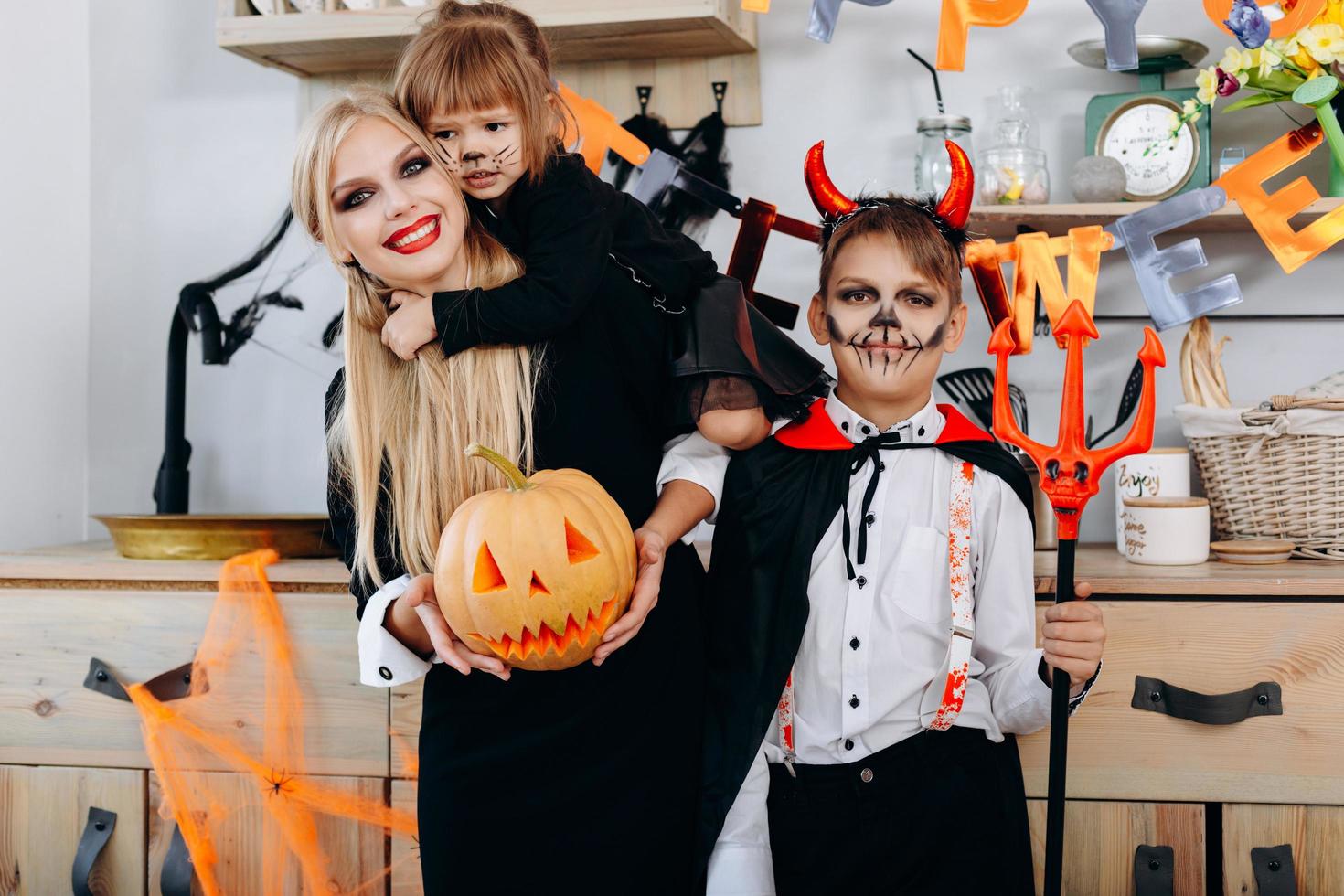 Lustige Familie in der Küche, die in Kostümen steht und in die Kamera schaut - Halloween-Konzept foto