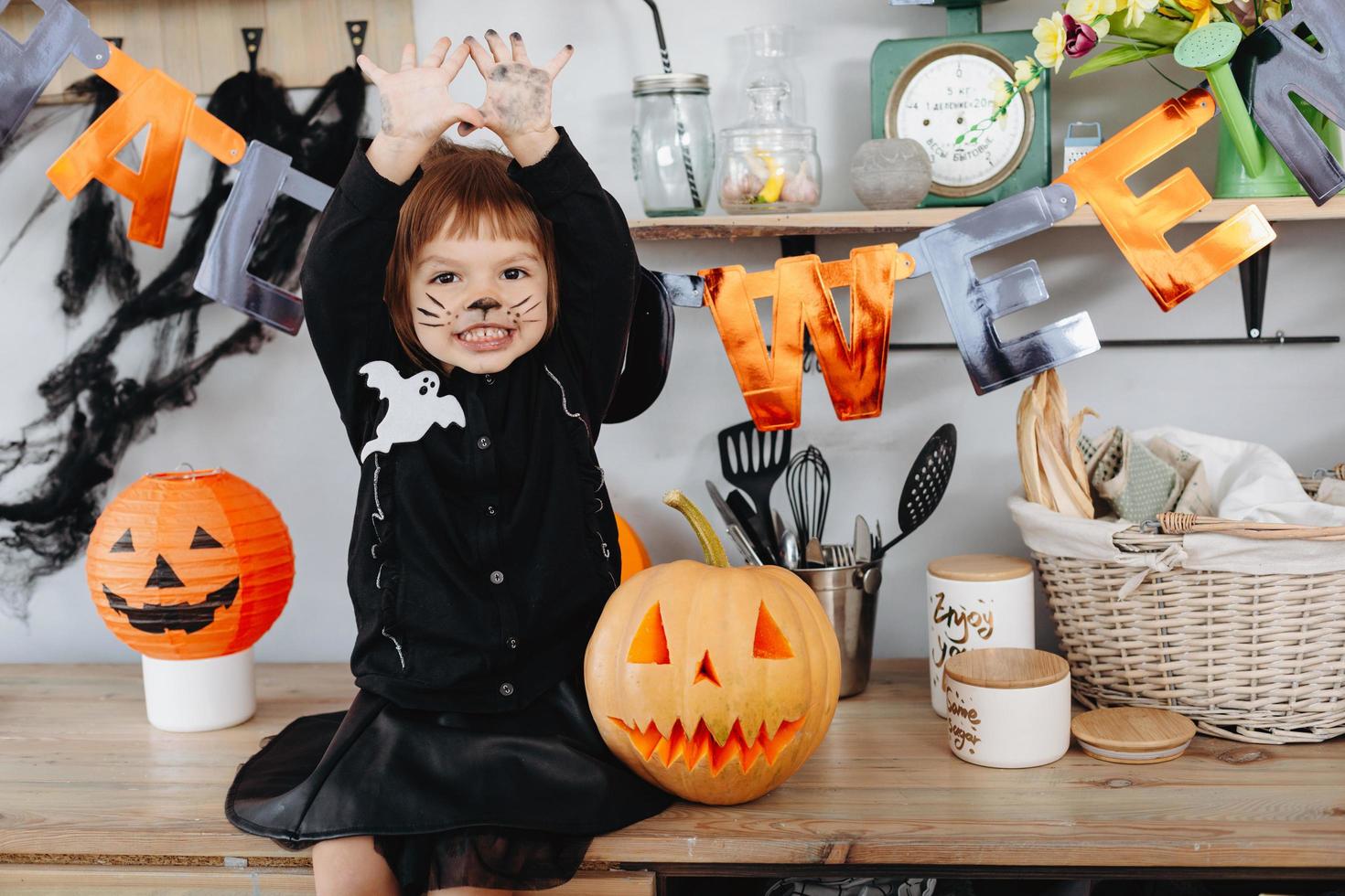 kleines Mädchen, das neben dem Kürbis sitzt und einen schmutzigen Arm zeigt, der in die Kamera schaut. - Halloween-Konzept foto