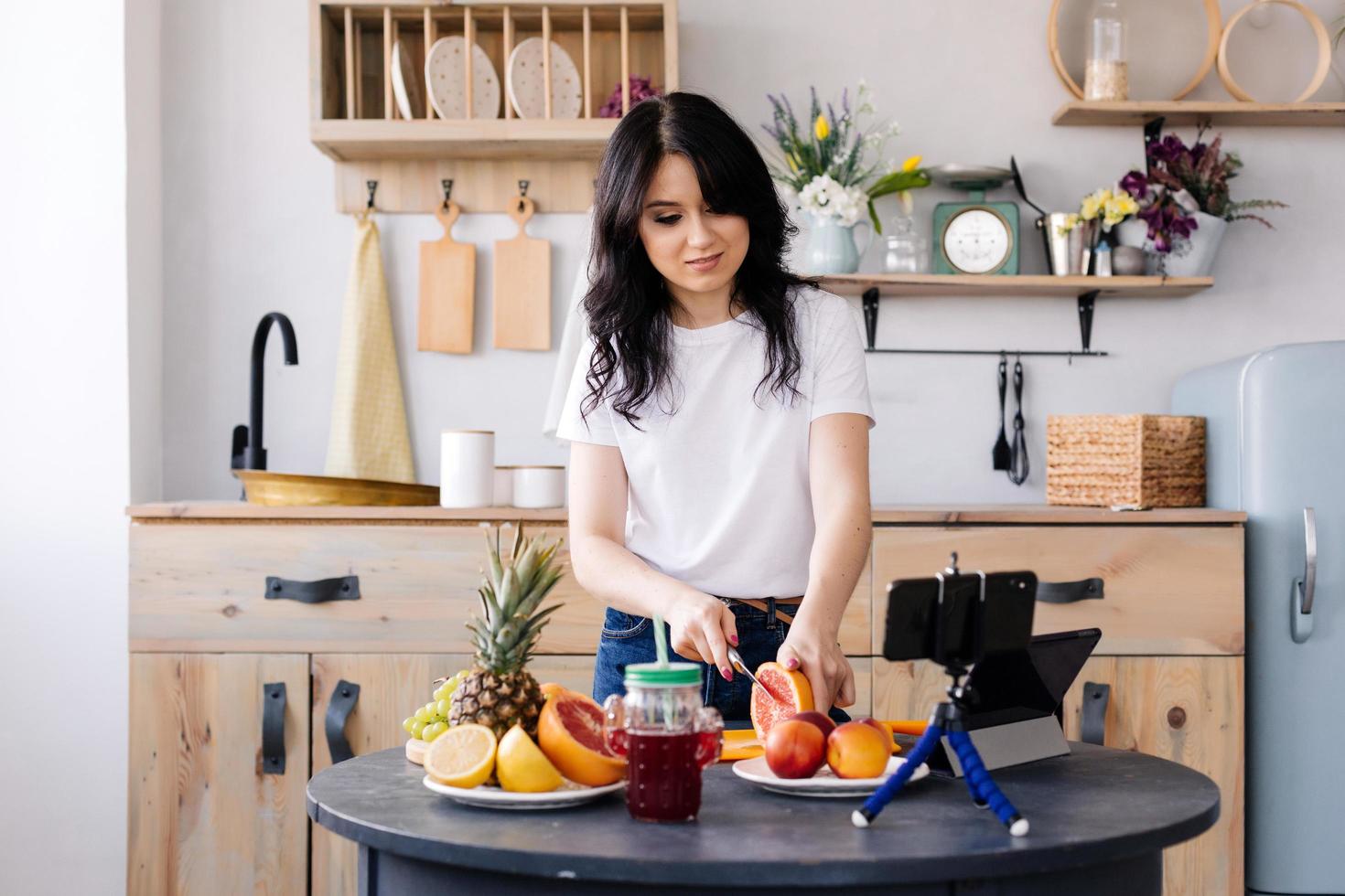 attraktives Mädchen bereitet Frucht-Smoothies zu foto