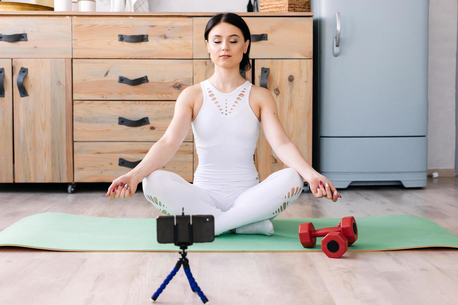 Mädchen macht Meditation und Übungen auf der Matte drinnen foto