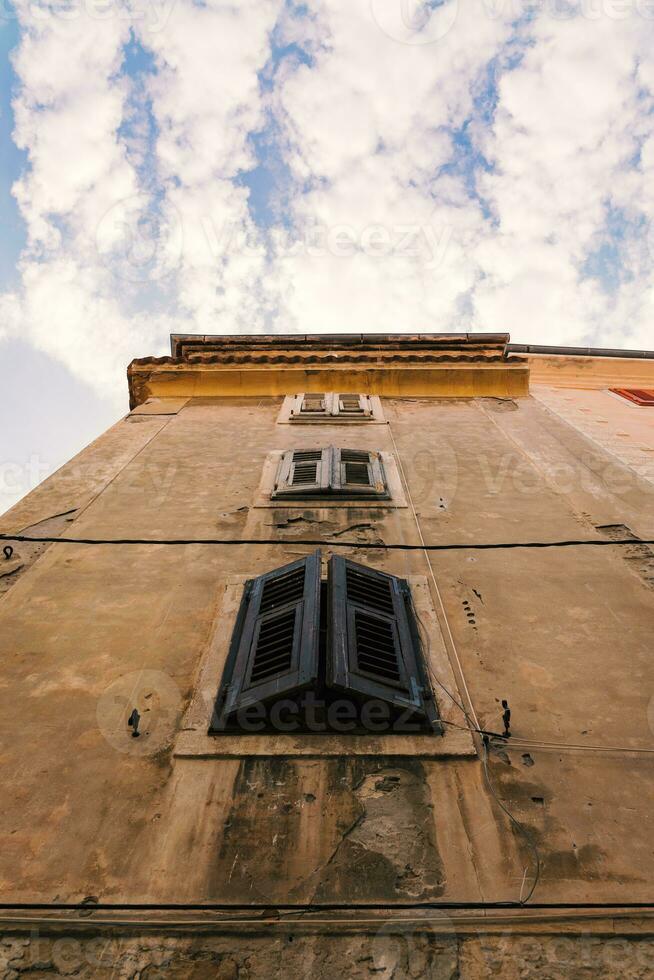 Unterseite Aussicht auf ein uralt Gebäude mit Fenster Fensterläden und Blau wolkig Himmel während Sonnenuntergang auf das Hintergrund foto