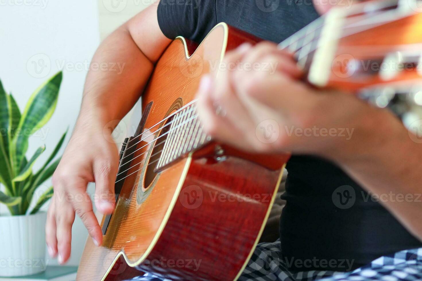 Nahansicht von ein Mann spielen Gitarre beim heim. foto