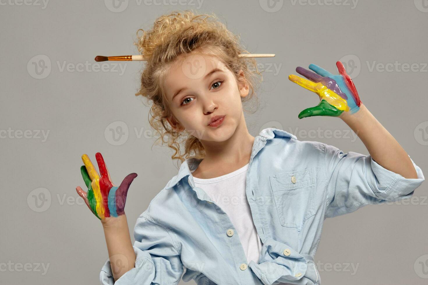 schön wenig Mädchen mit ein gemalt Finger ist posieren auf ein grau Hintergrund. foto