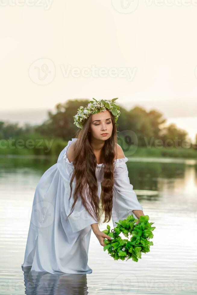 schön Frau auf das Fluss Bank. rustikal Frau mit ein Kranz im ein transparent Kleid foto