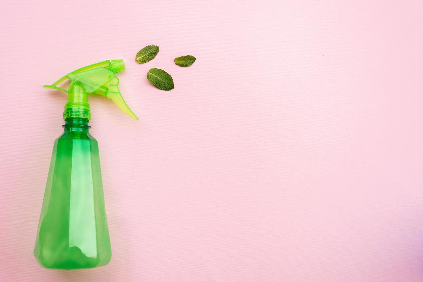 Waschmittel grüne Flasche auf rosa Hintergrund sprühen frische Minzblätter. - Platz kopieren foto