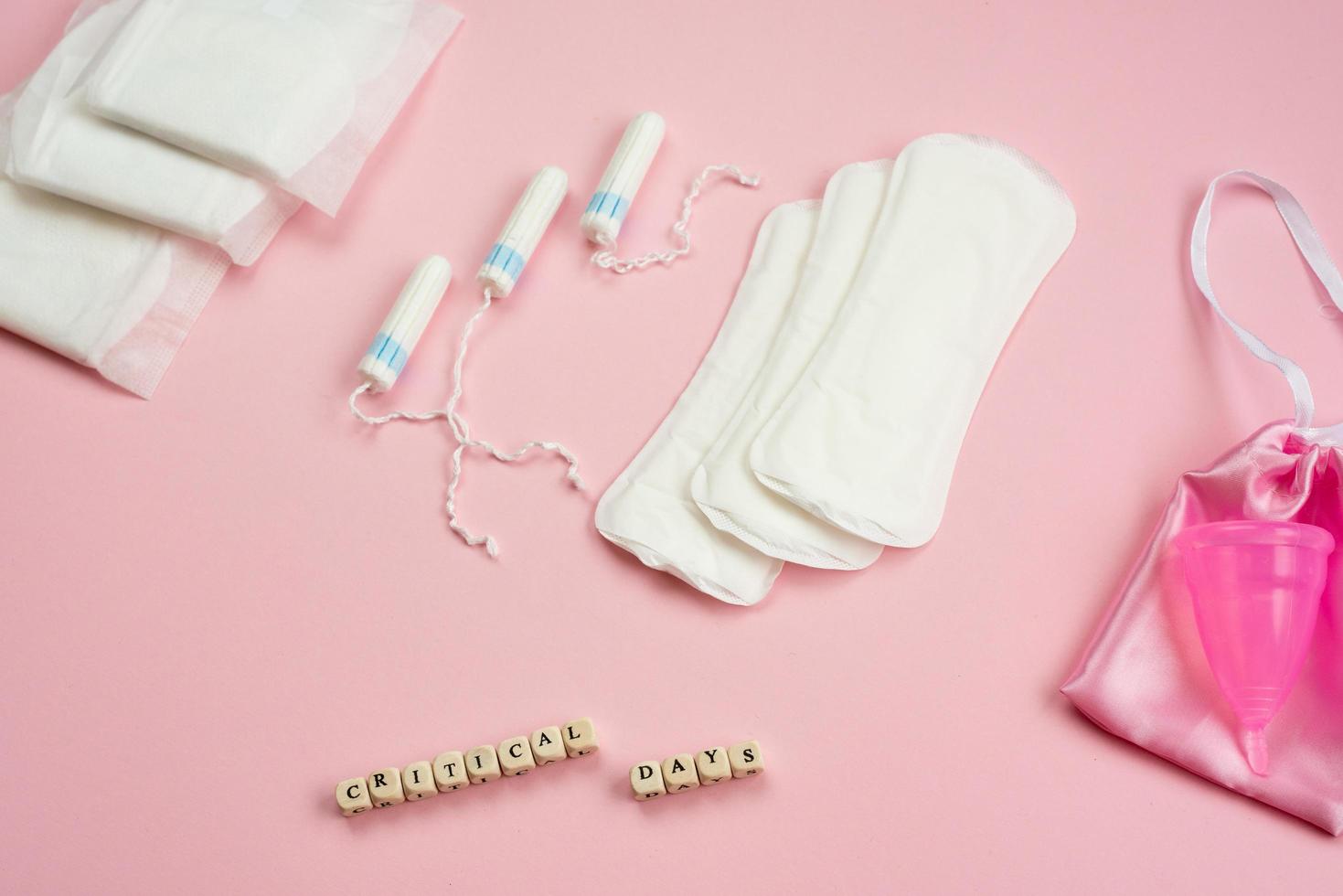 weiße Tampons, Menstruationstasse, weibliche Dichtungen auf rosa Hintergrund. Konzept der kritischen Tage, Menstruation foto