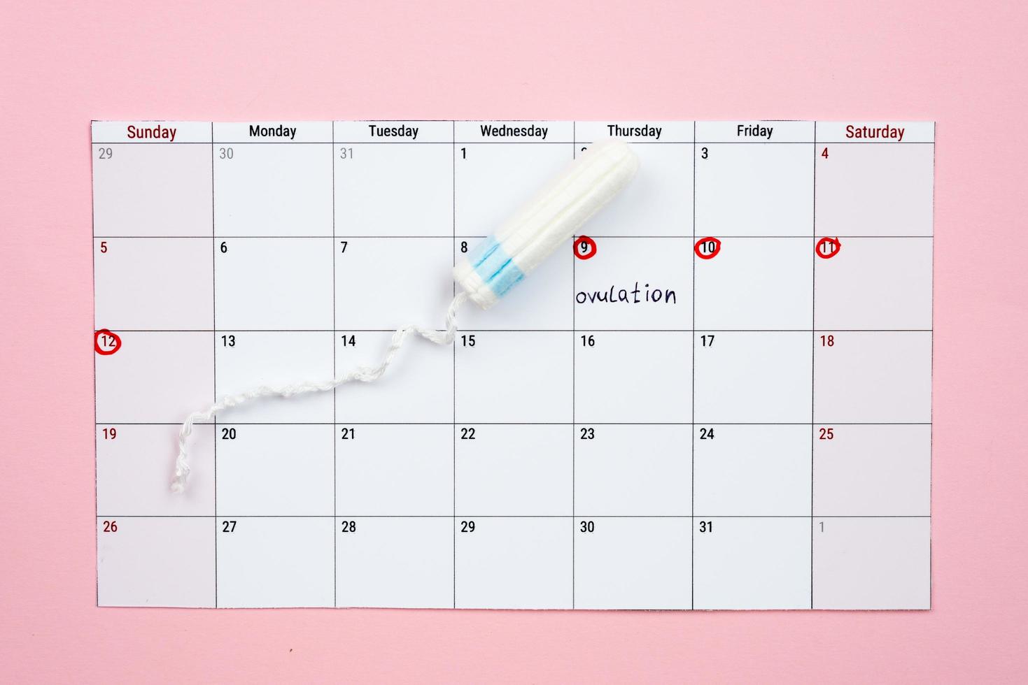 Menstruationskalender und Frauentampon, die auf rosa Hintergrund liegen. - Bild foto