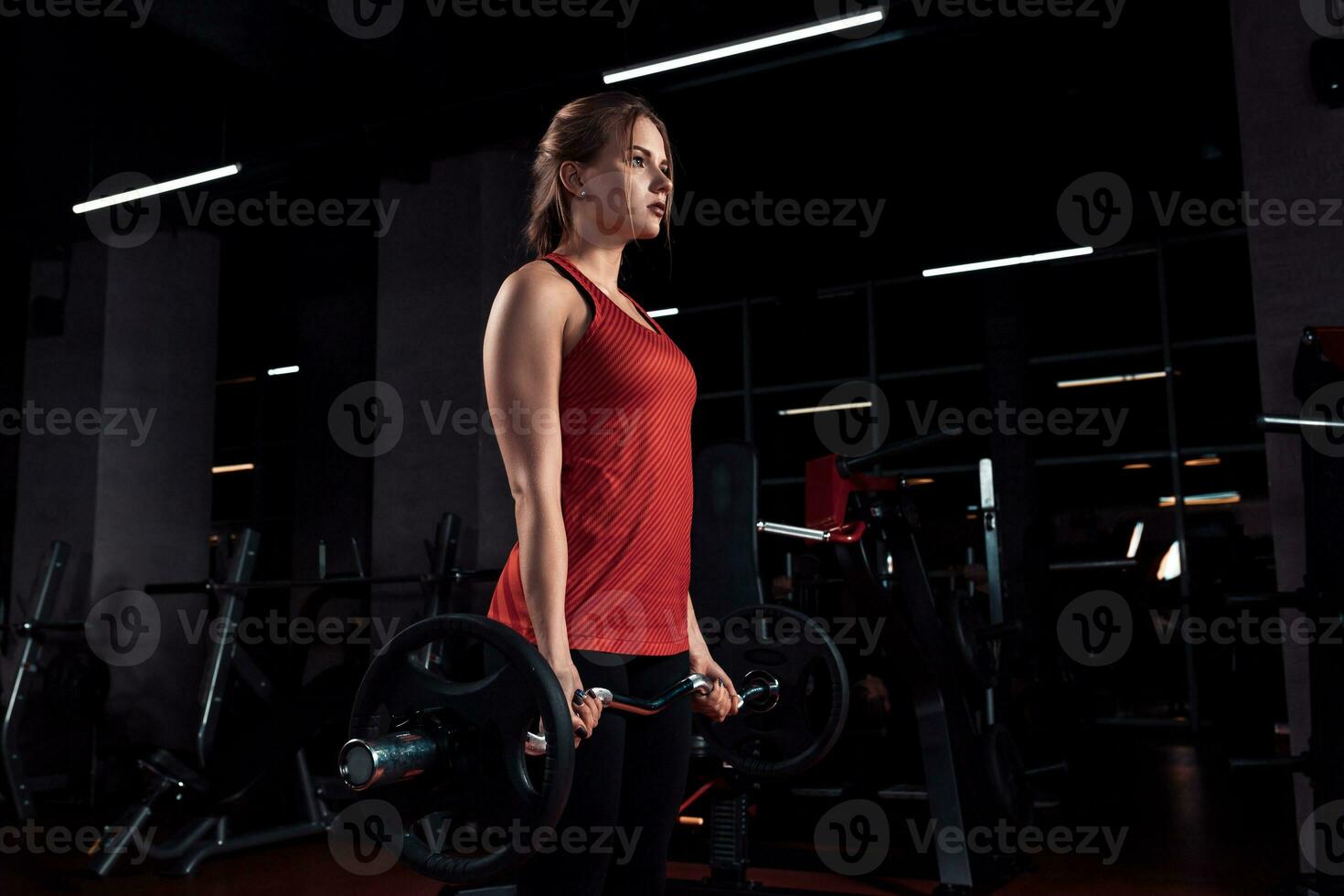 jung schön Frau tun Übung mit Bar im ein Fitnessstudio. sportlich Mädchen tun trainieren im ein Fitness Center. foto