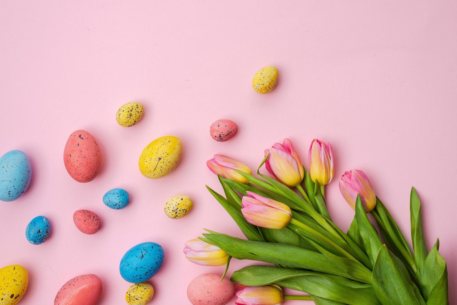 Osterhintergrund, bunte Eier und Tulpenstrauß liegen auf einem weißen rosa Tisch. - Platz kopieren foto