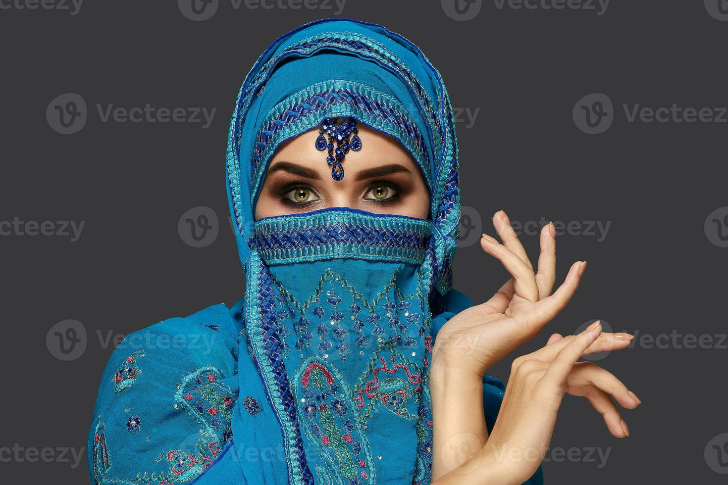 Studio Schuss von ein jung schön Frau tragen das Blau Hijab dekoriert mit Pailletten und Schmuck. Arabisch Stil. foto