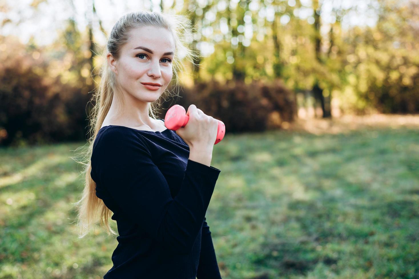 Mädchen posiert mit Hantel in der Hand im Freien. foto