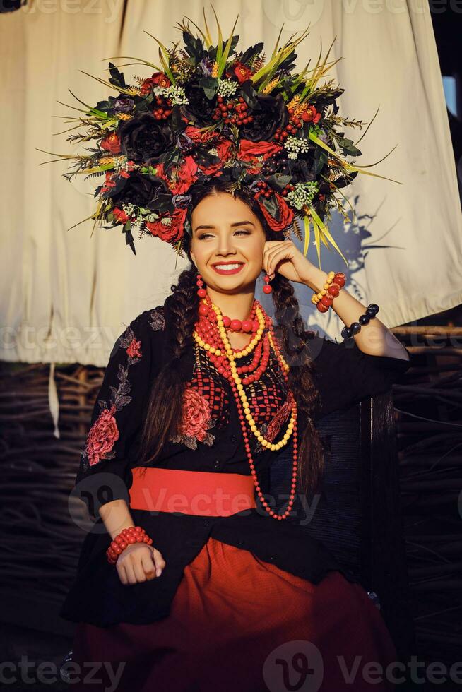 Brünette Mädchen im ein Weiß ukrainisch authentisch National Kostüm und ein Kranz von Blumen ist posieren gegen ein Terrasse. Nahansicht. foto