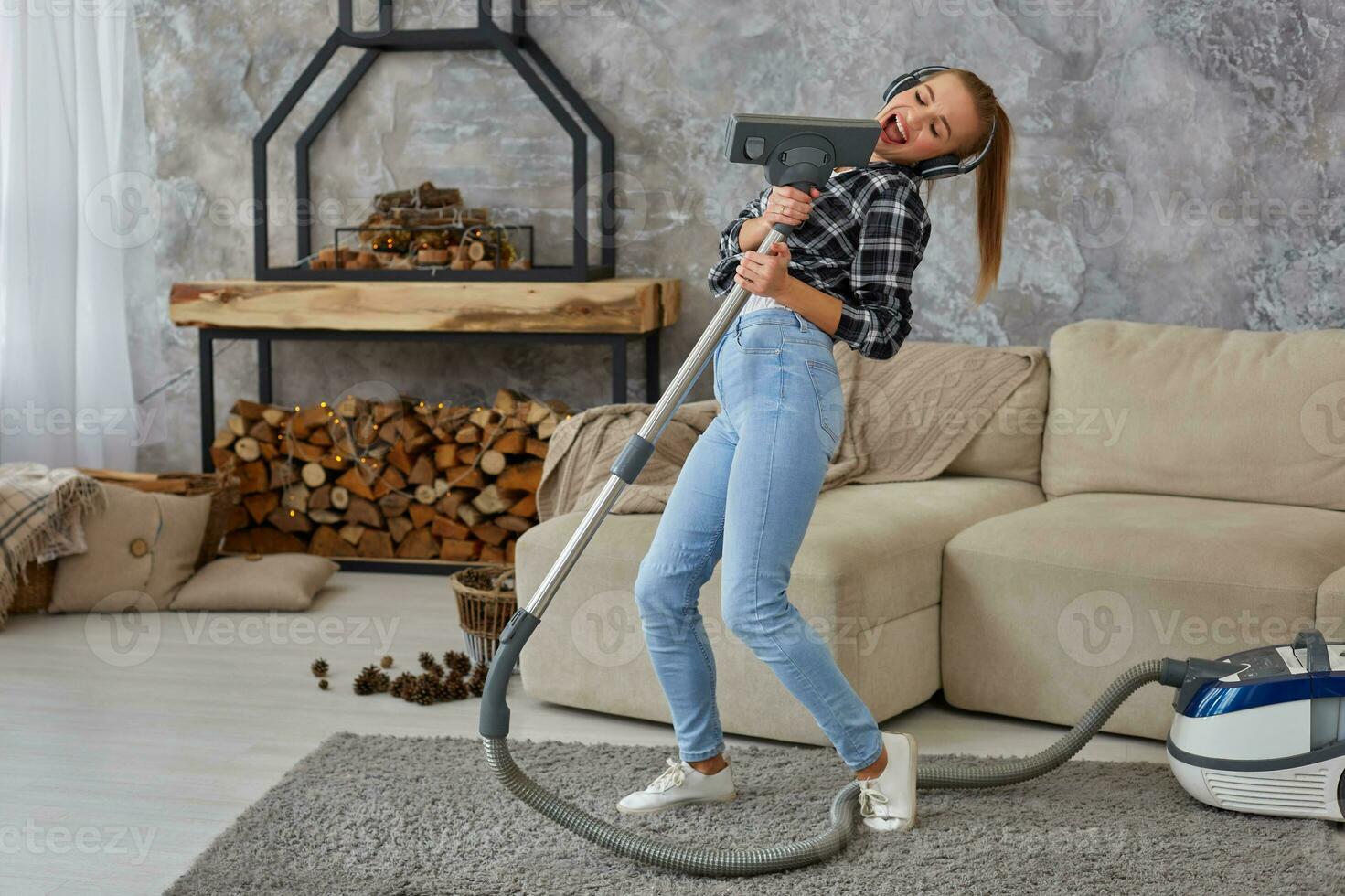 heiter jung Frau genießen Solo Singen mit Vakuum Reiniger während Reinigung Haus foto