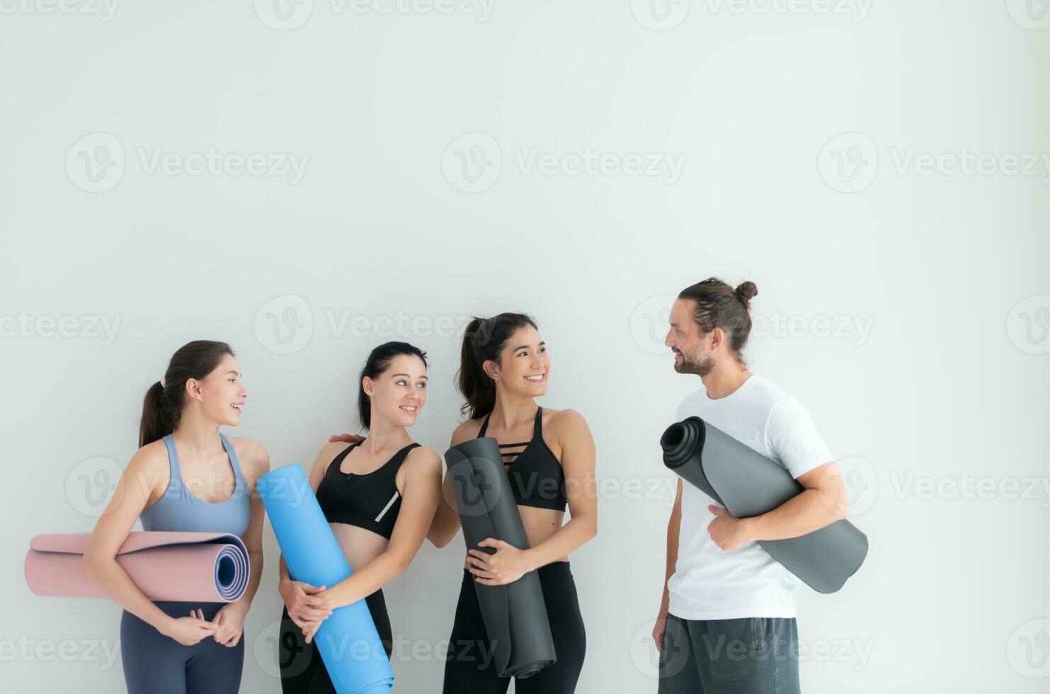 ein Gruppe von weiblich und männlich Sportler stand auf und geplaudert friedlich im das Studio Vor Anfang mit das Yoga Klasse. foto