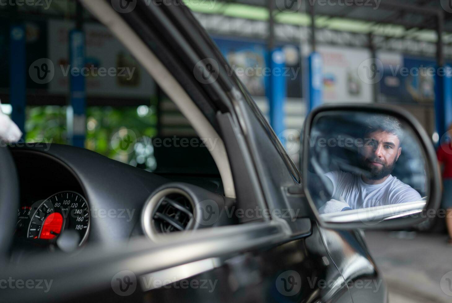 ein jung Mann Fahrzeug Techniker Arbeiten Innerhalb ein Auto beim ein Auto Reparatur Geschäft. foto