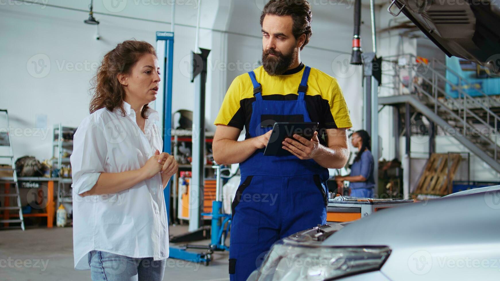 lizenziert Mechaniker Hören zu Kunde im Reparatur Geschäft, mit Laptop zu schreiben Nieder Auto Änderungen erforderlich. Experte im Garage mit afrikanisch amerikanisch Klient, Hören zu ihr Anfragen zum Fahrzeug Tuning foto