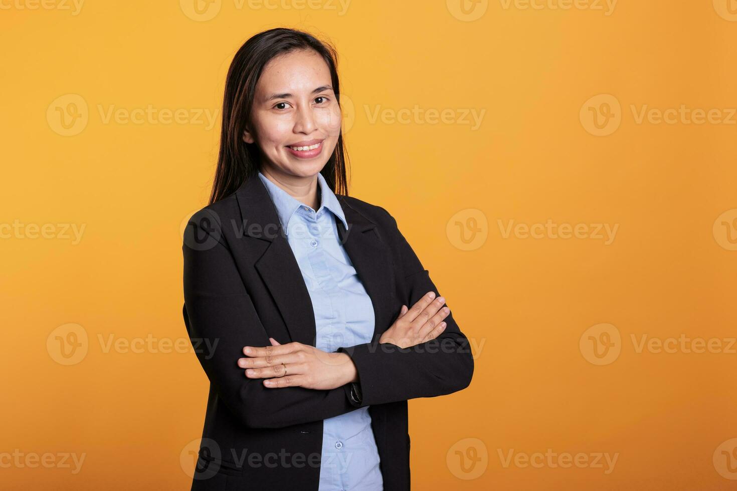 erfolgreich froh Frau Stehen im Arm gekreuzt posieren Über Gelb Hintergrund, lächelnd beim Kamera während Studio schießen. lächelnd asiatisch Modell- mit heiter Ausdruck genießen brechen Zeit foto