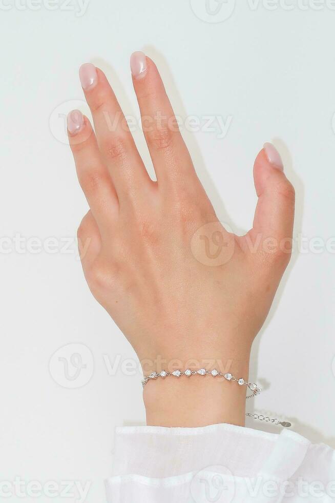 Frau Hand und Handgelenk tragen Silber Zirkon funkeln Armband einstellen gegen ein Weiß Hintergrund. foto