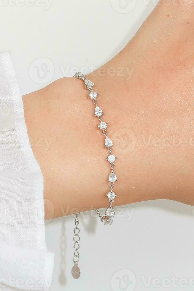 Frau Handgelenk tragen Silber Zirkon funkeln Armband einstellen gegen ein Weiß Hintergrund. foto