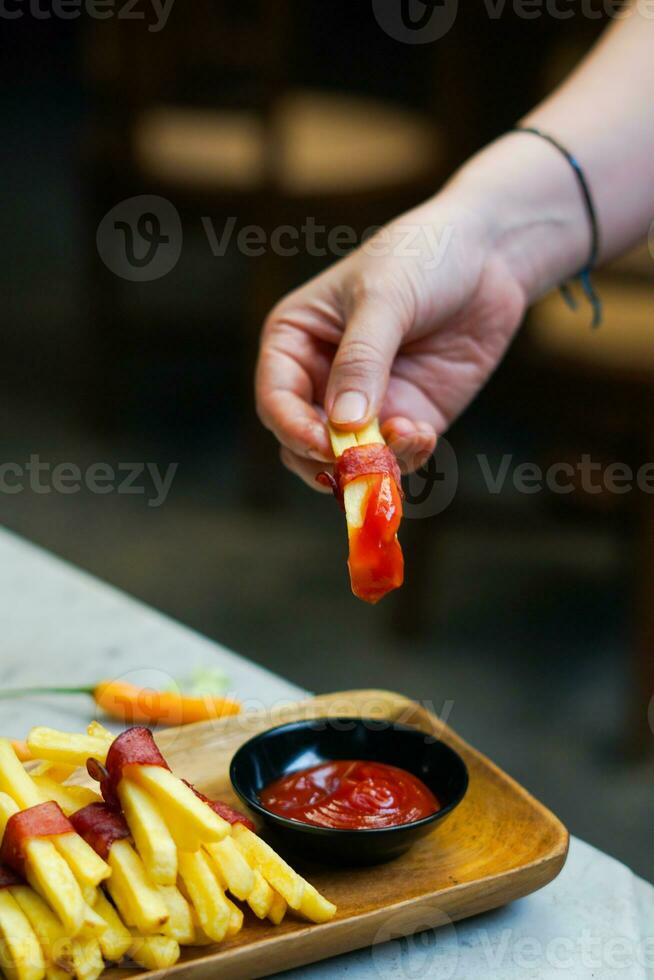 abgeschnitten Hand Eintauchen Kartoffel Scheibe zu Soße schließen oben foto
