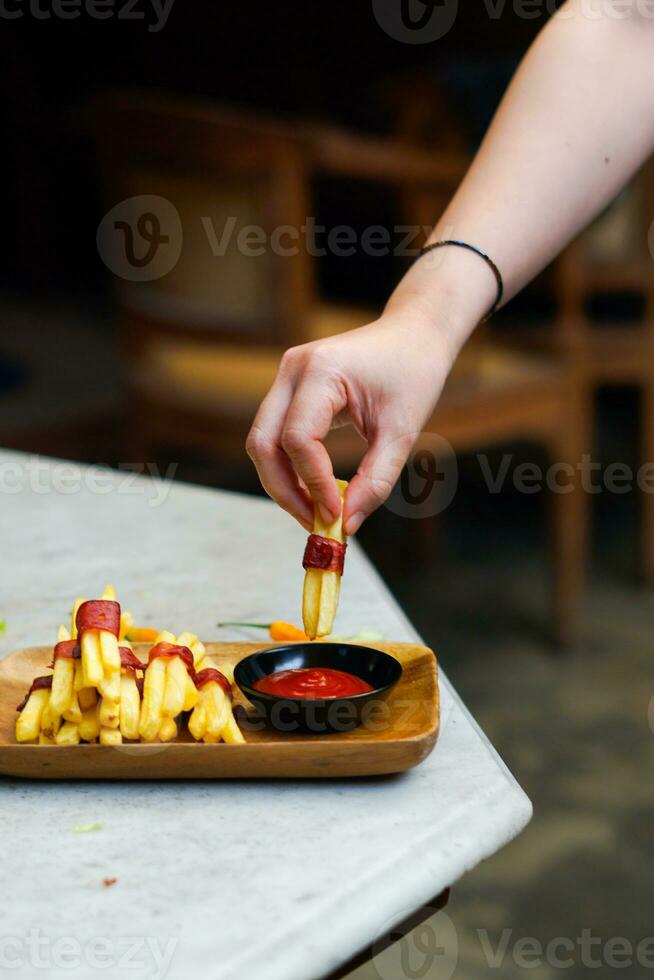abgeschnitten Hand Eintauchen Kartoffel Scheibe zu Soße schließen oben foto