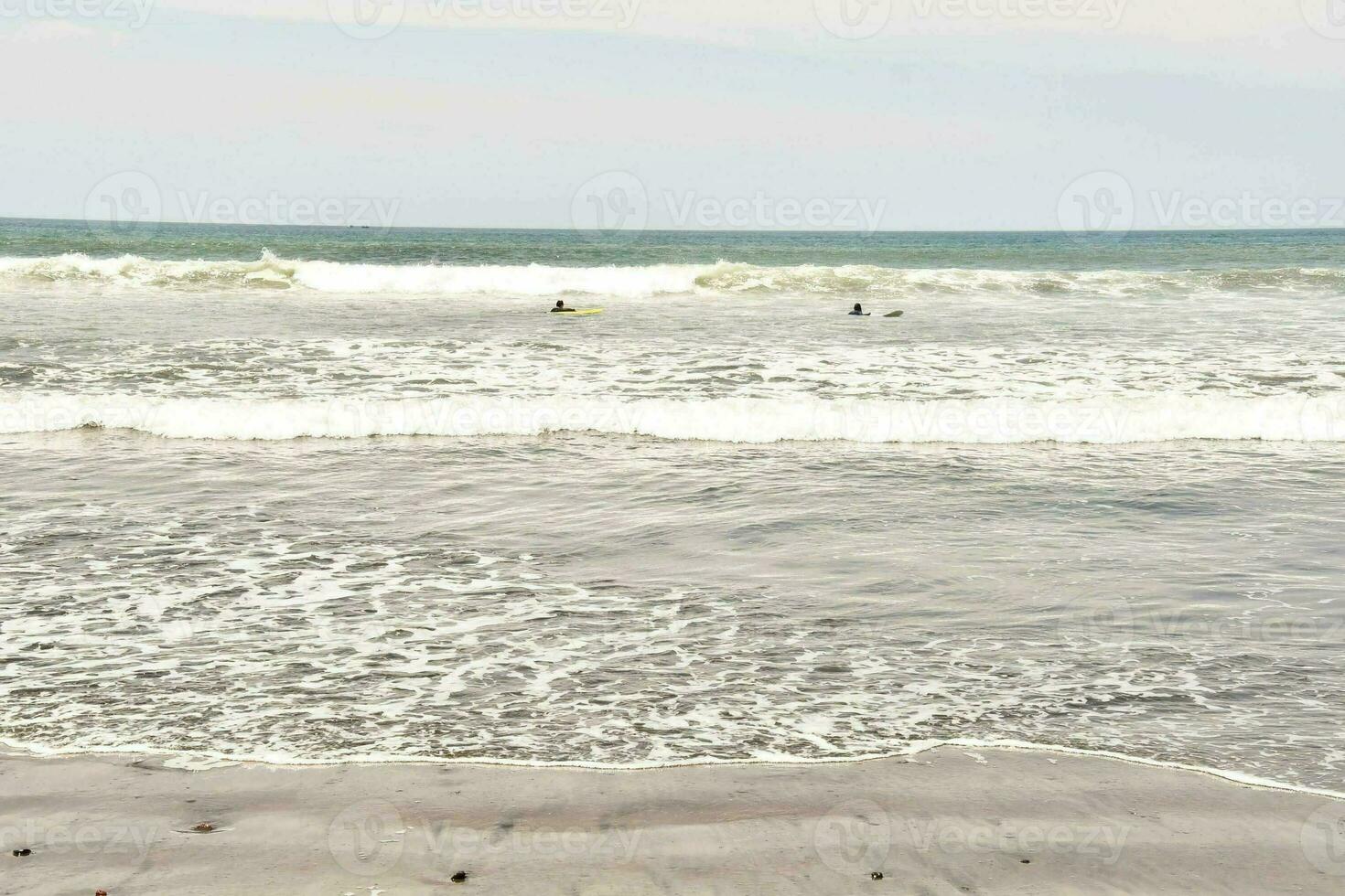 ein sandig Strand mit Wellen und Felsen foto