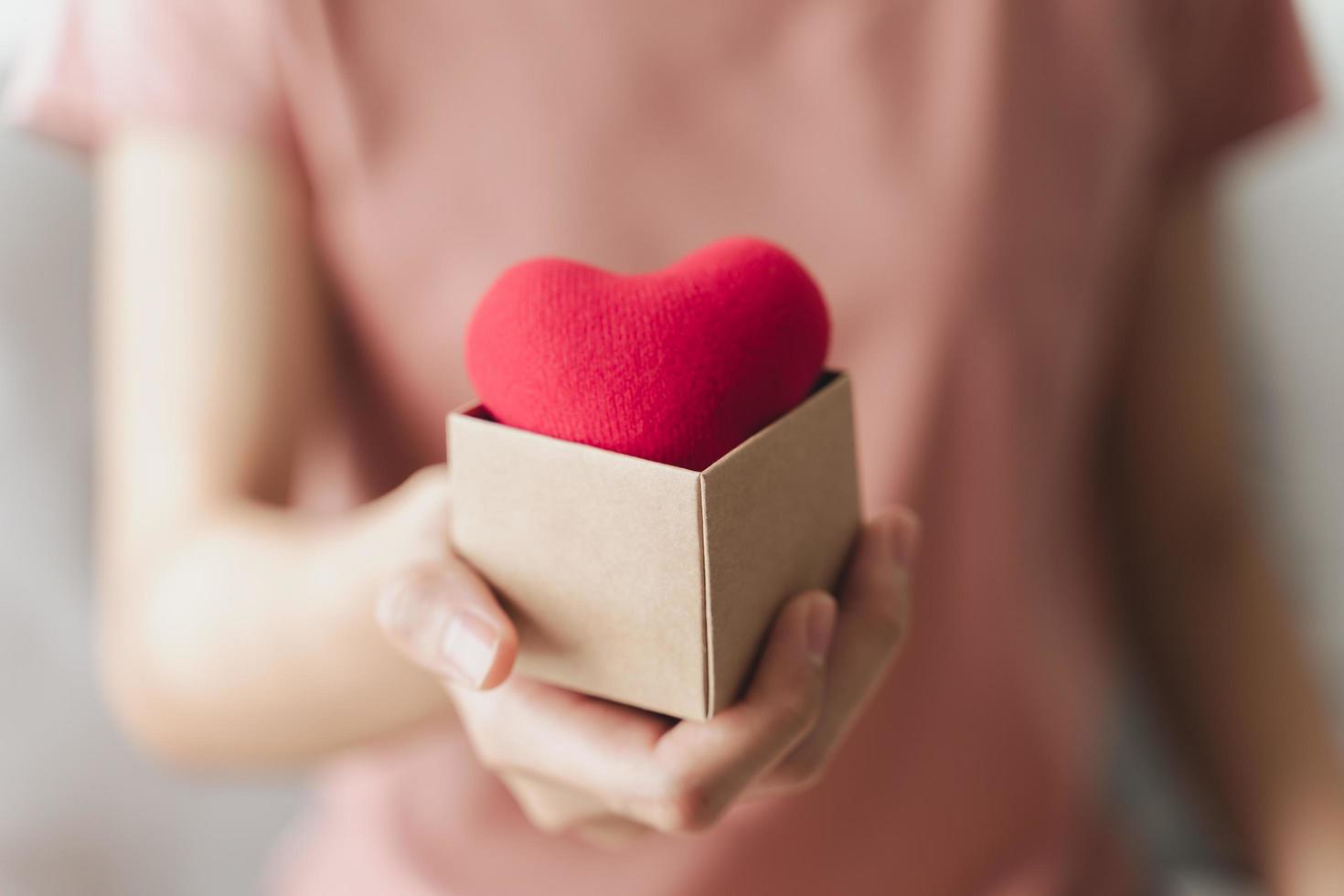 Frau mit Geschenkbox mit rotem Herzen, Liebe, Krankenversicherung, Spende, glücklicher Wohltätigkeits-Freiwilliger, Welttag der psychischen Gesundheit, Weltherztag, Valentinstag foto
