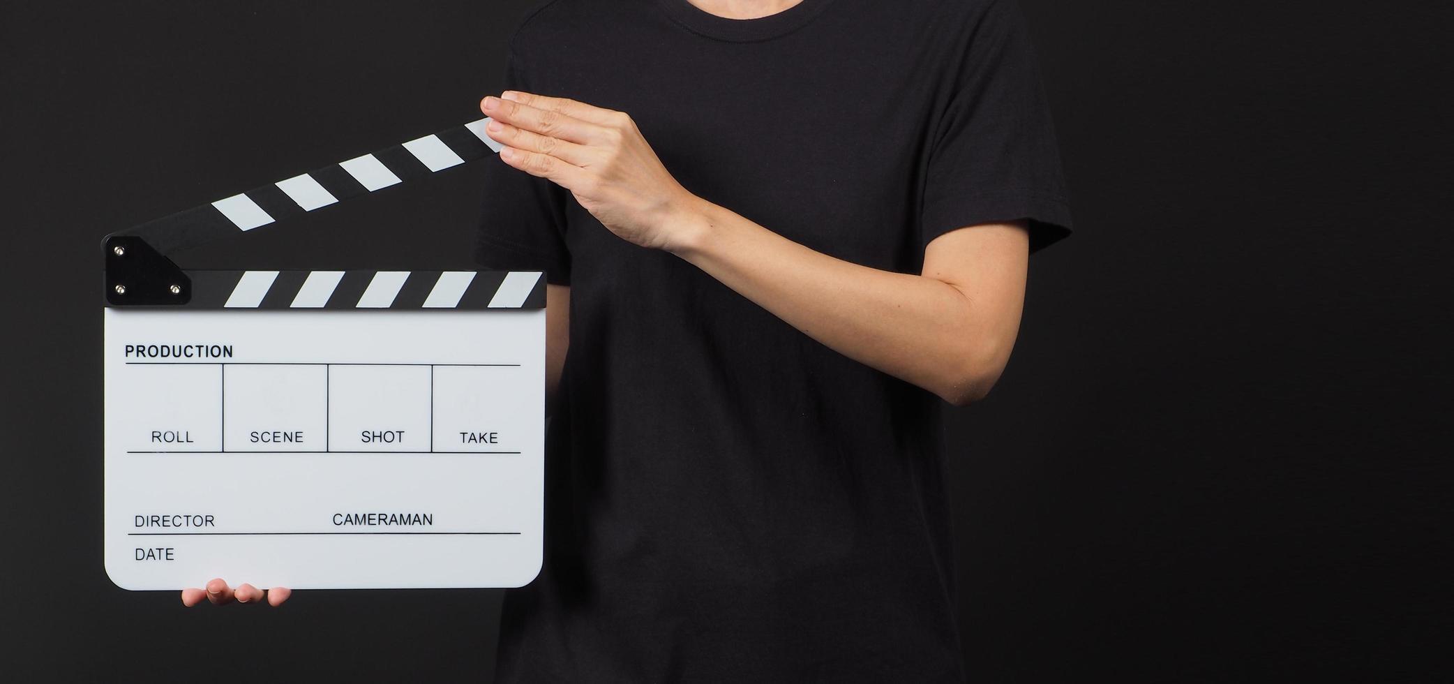 weibliches Modell hält Klappe oder Filmtafel bei Studioaufnahmen. Es wird in der Videoproduktion und in der Kinoindustrie auf schwarzem Hintergrund verwendet. foto