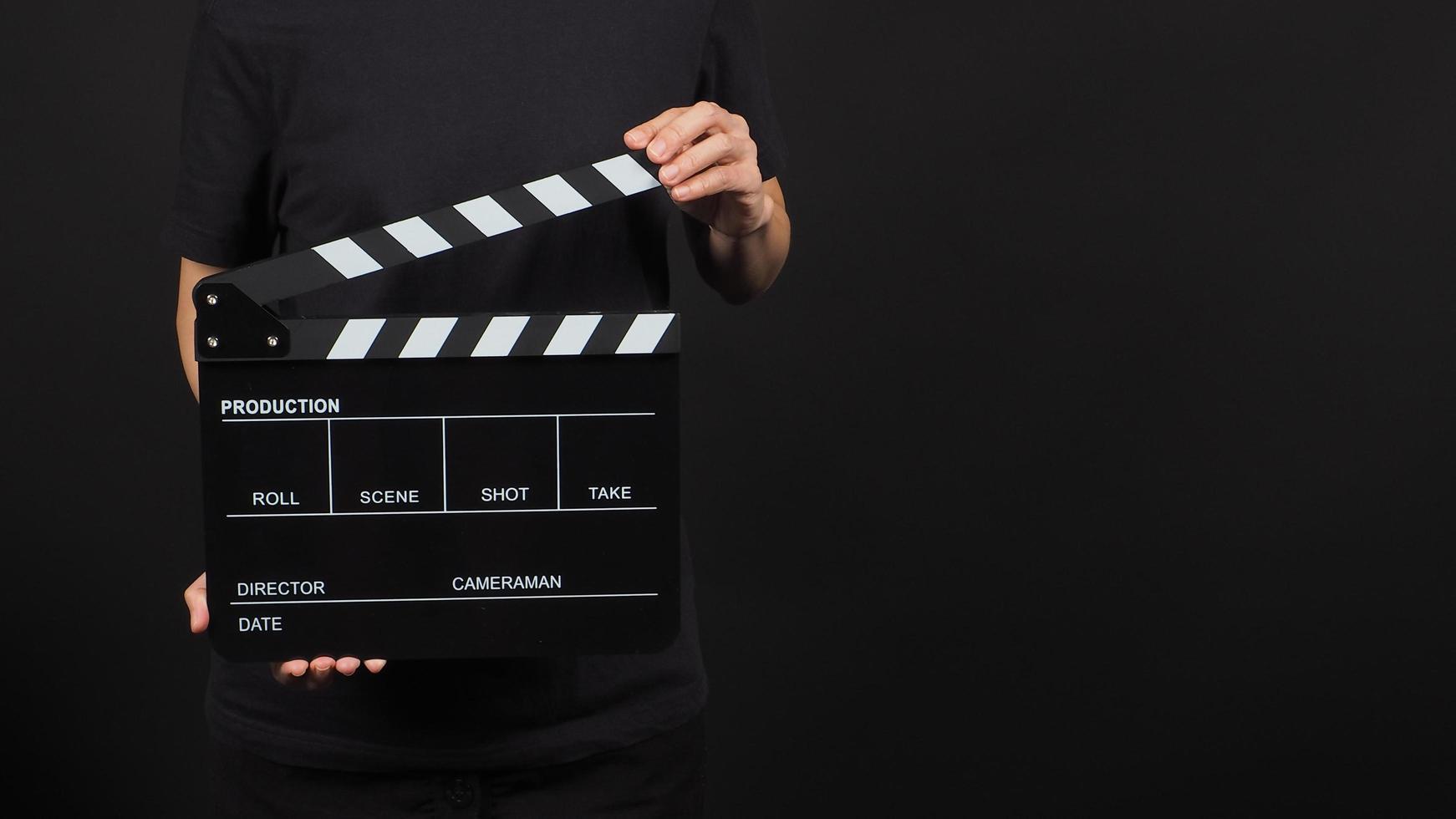 Frau hält Filmklappe oder Filmtafel bei Studioaufnahmen. Es wird in der Videoproduktion und in der Kinoindustrie auf schwarzem Hintergrund verwendet. foto