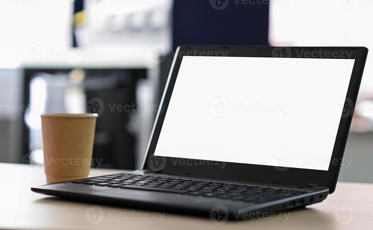 abgeschnittene Aufnahme eines leeren Laptop-Bildschirms mit Kaffee zum Mitnehmen auf dem Tisch im Büro. foto