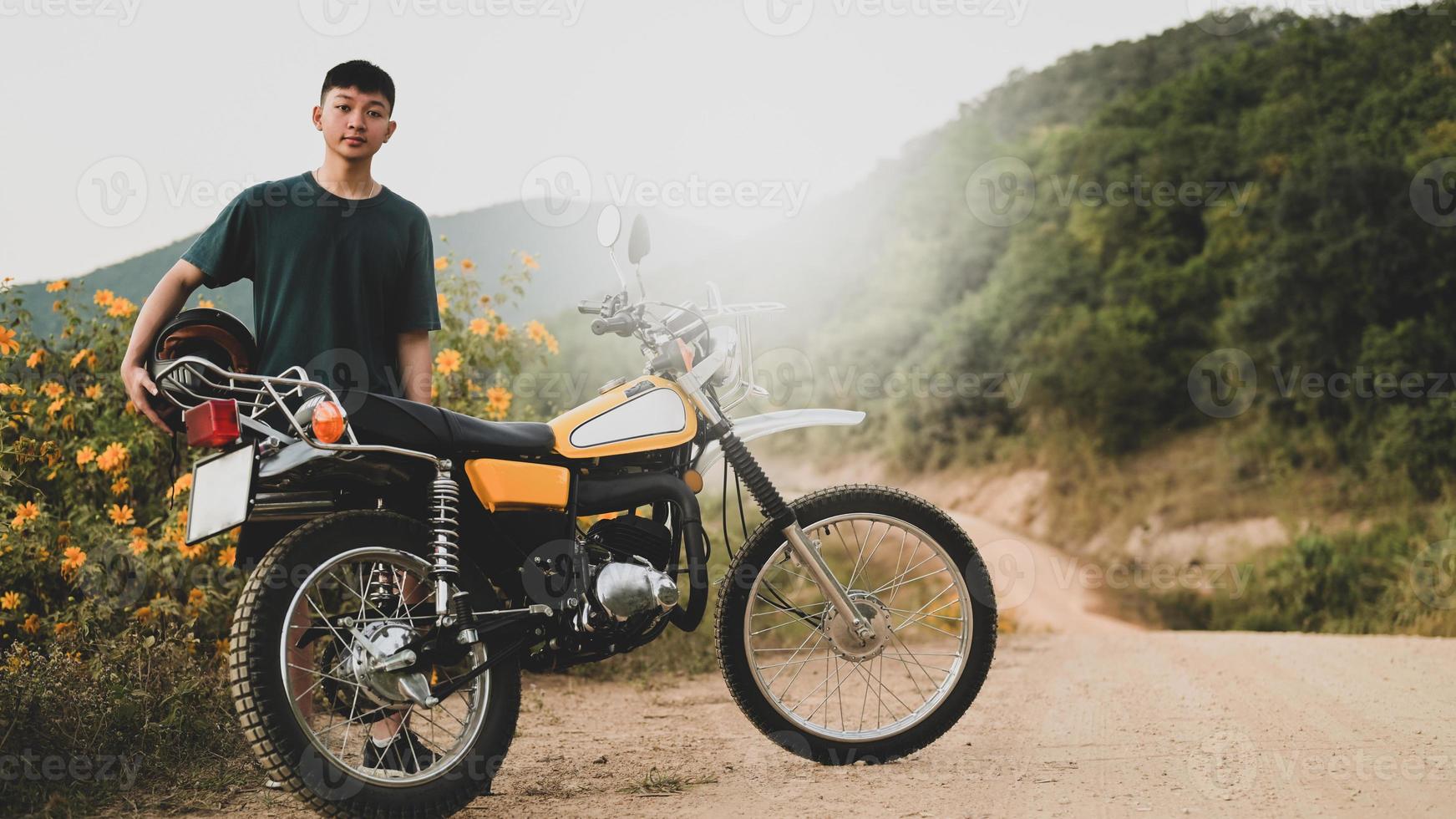 ein Teenager und ein klassisches Enduro-Motorrad auf einer steinigen Straße. foto