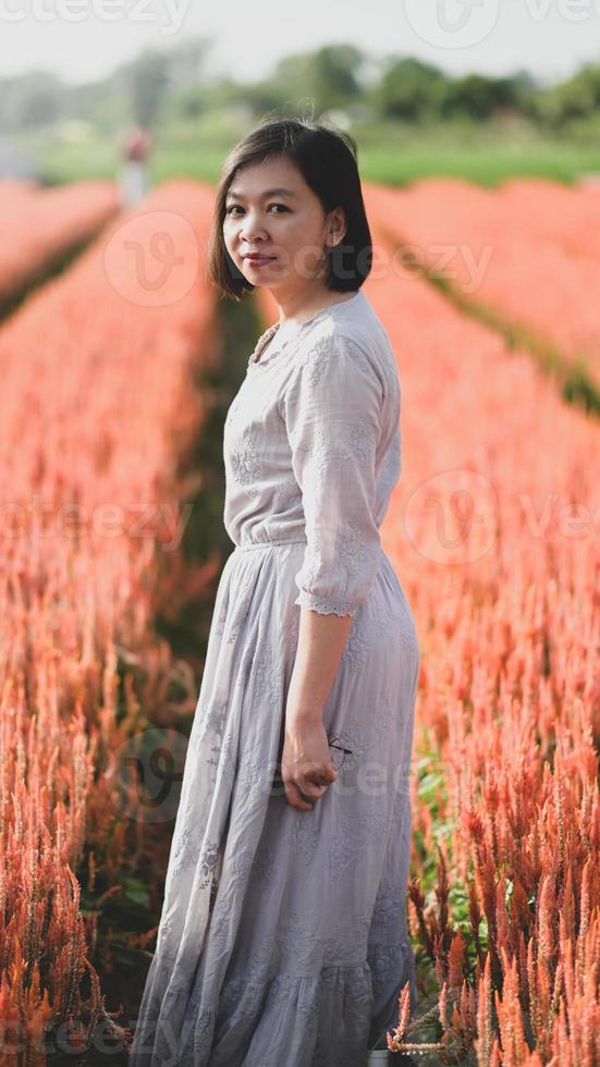 asiatische Frau, die glücklich im Blumengarten spazieren geht und fotografiert. foto