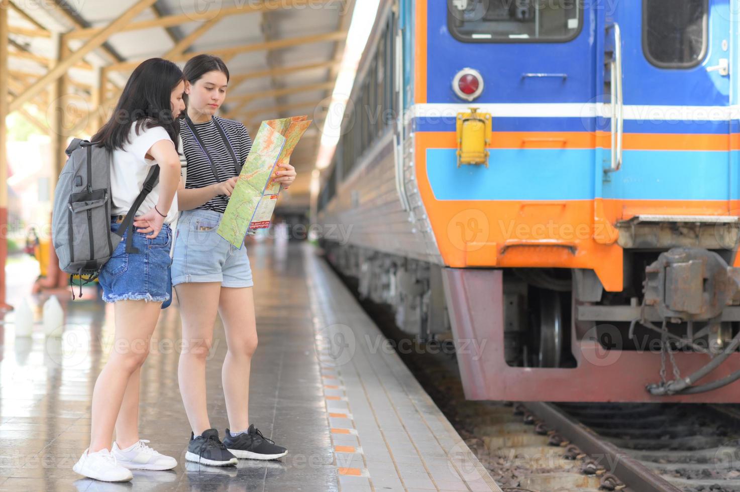 zwei Mädchen im Teenageralter, die eine Karte betrachten, um mit dem Zug zu reisen. foto
