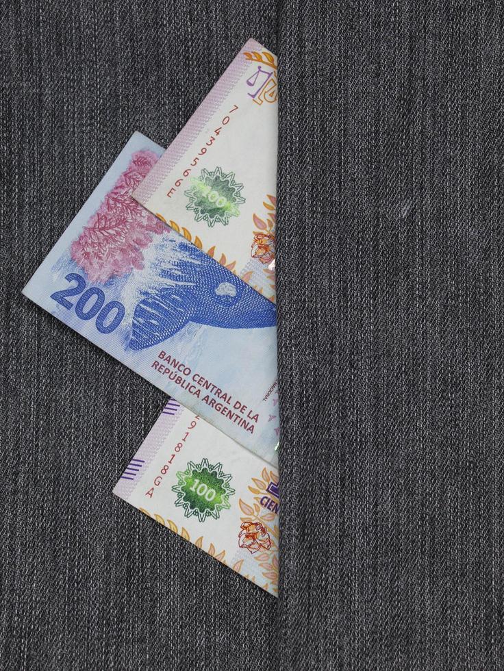 argentinische Banknoten unterschiedlicher Stückelung zwischen blauem Denim-Stoff foto