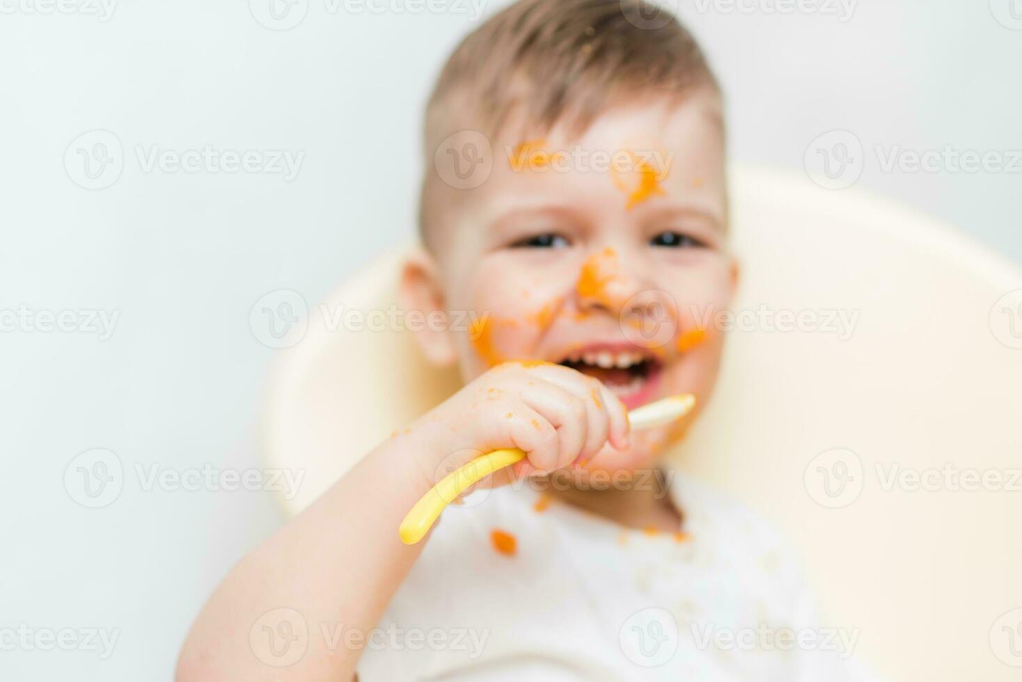 süß Baby Junge während Essen verschmiert seine Gesicht mit ein Kürbis foto