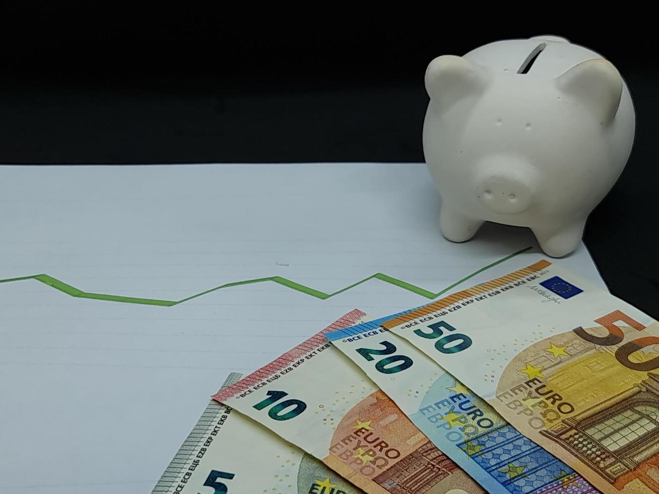 Europäische Banknoten und Sparschwein im Hintergrund mit steigender grüner Trendlinie foto