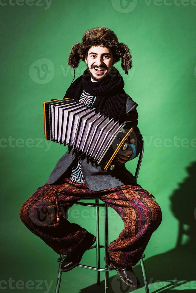 ein sehr positiv Mann mit ein Akkordeon posieren im das Studio foto