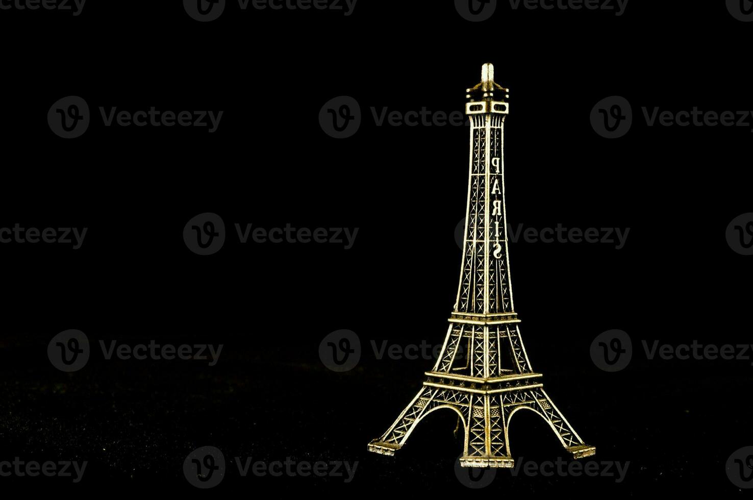 ein Gold Eiffel Turm auf ein schwarz Hintergrund foto