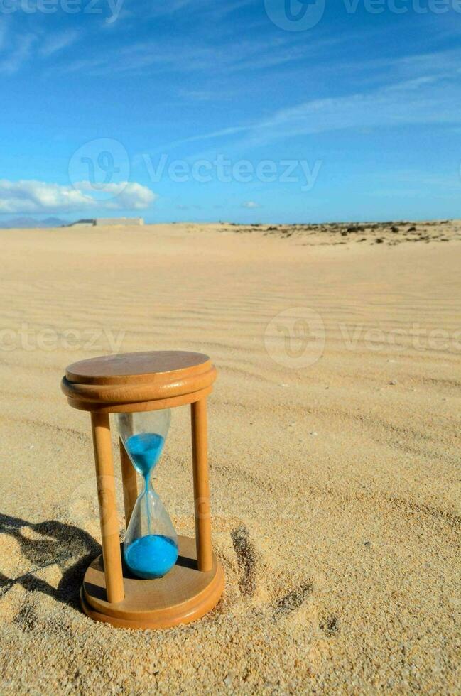 ein Sanduhr Sitzung auf das Sand im das Mitte von ein Wüste foto