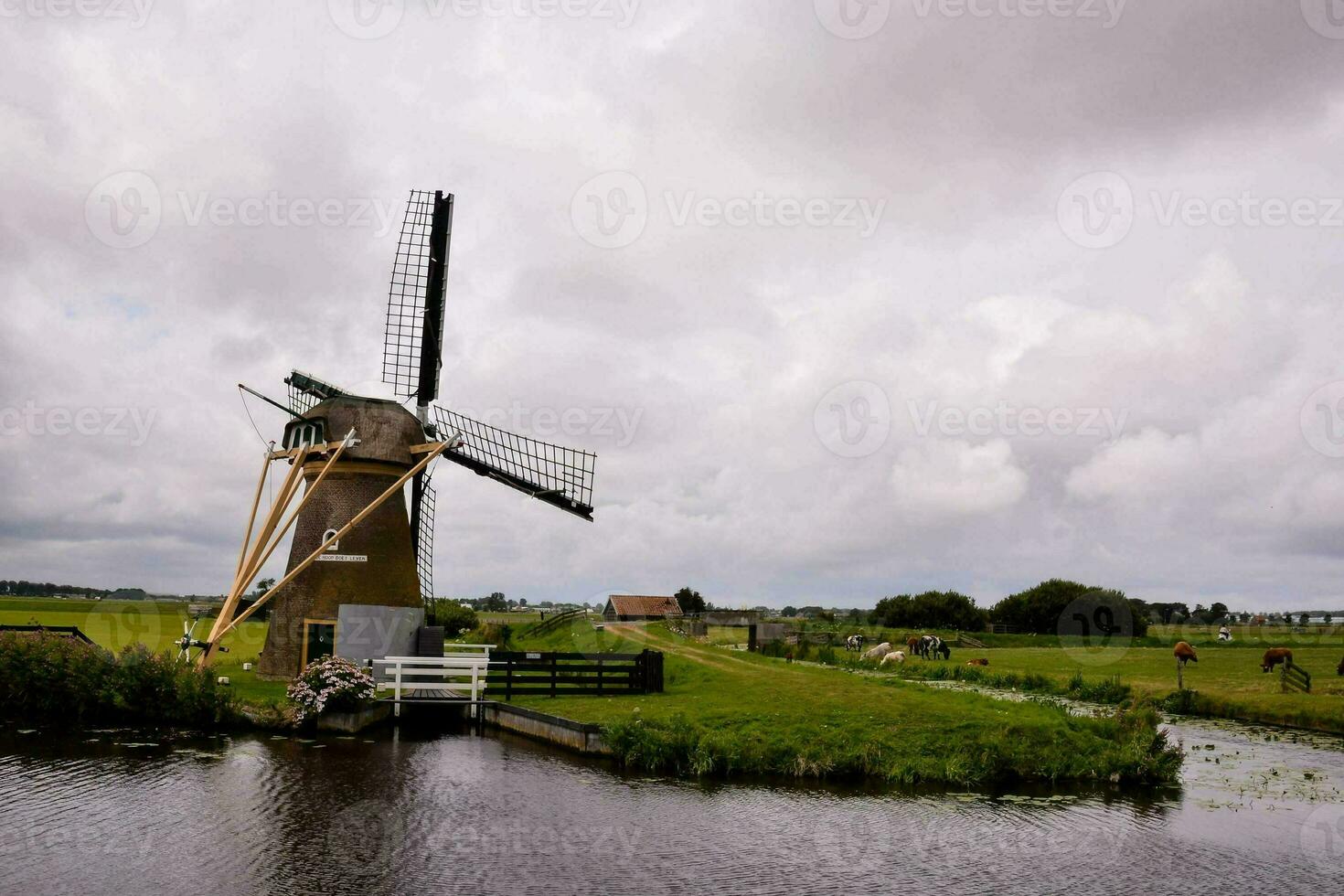 ein Windmühle ist Nächster zu ein Fluss im ein Feld foto