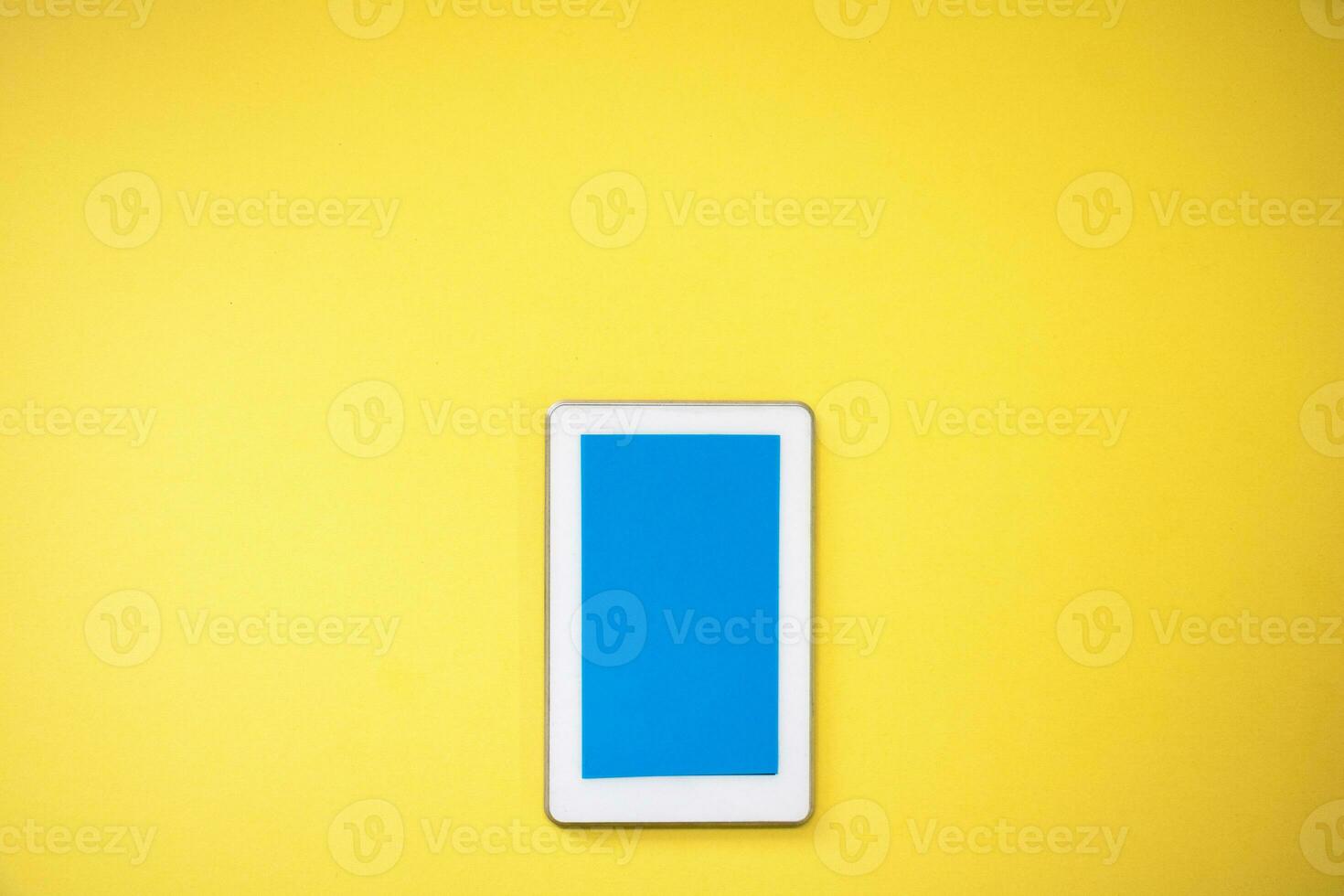 ein Weiß Tablette mit ein Blau Bildschirm auf ein Gelb Hintergrund foto